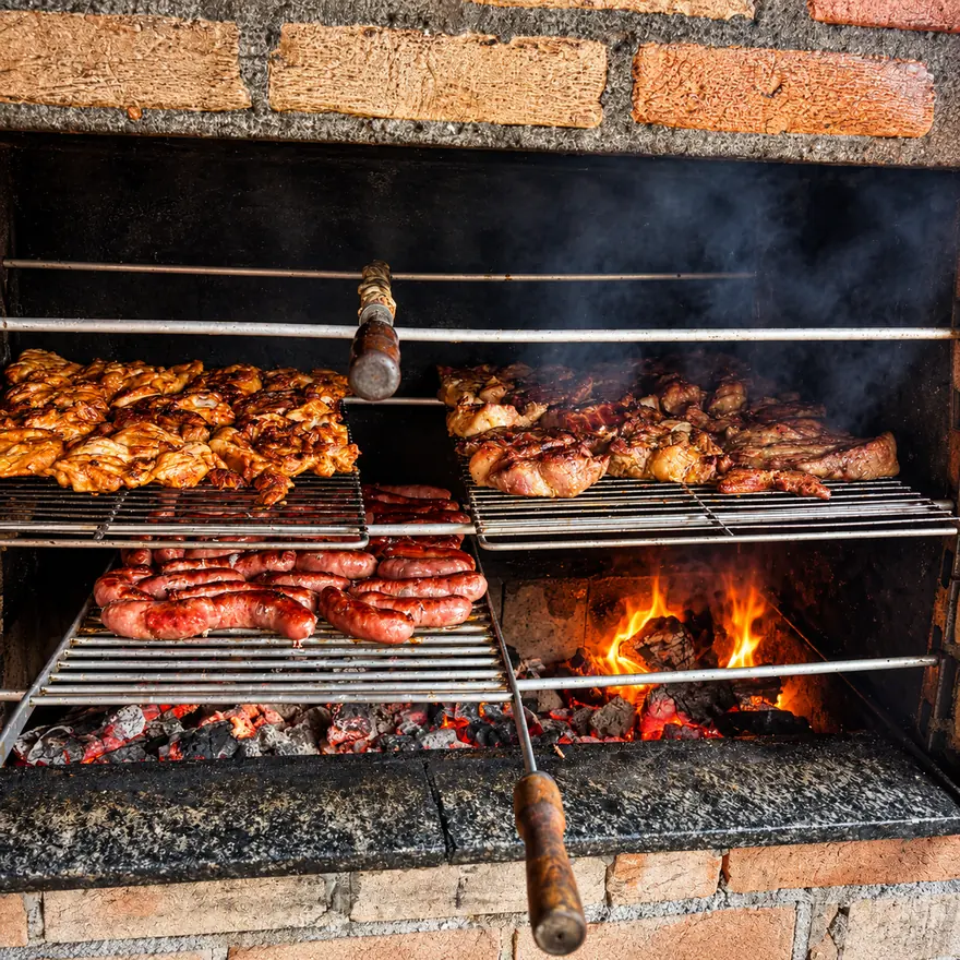 Frango, linguiça e carnes assando na churrasqueira a carvão